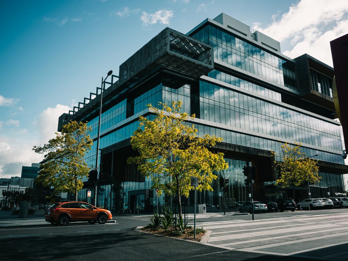 Four-story commercial building with a dark steel frame and a full glass curtain-wall exterior
